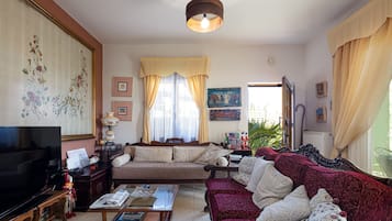 Sala de estar com televisão, sofá e mesa de centro.