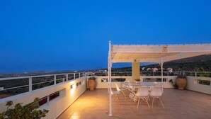 Eine Terrasse mit Tisch und Stühlen, einer Pergola und Blick auf die Landschaft.