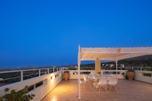 Eine Terrasse mit Tisch und Stühlen, einer Pergola und Blick auf die Landschaft.