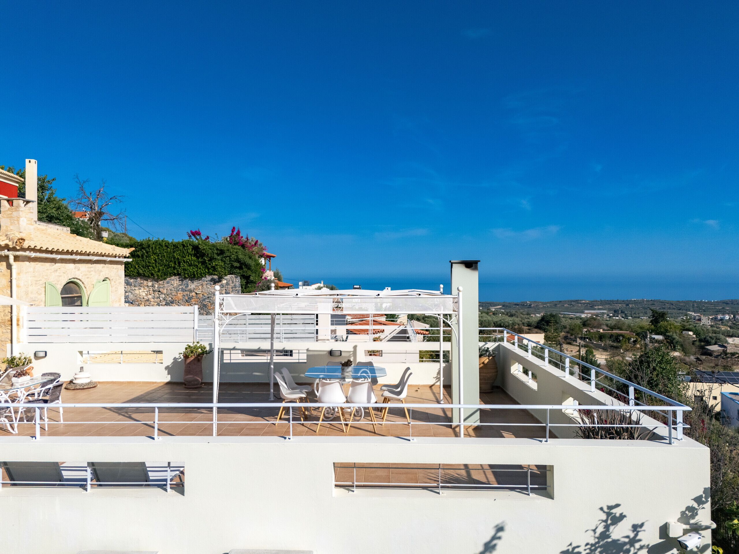 Eine Dachterrasse mit Sitzgelegenheiten im Freien und Blick auf das Meer.