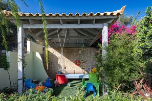 Ein überdachter Außenbereich mit einer Pergola, einer Steinmauer und einer Schaukel.