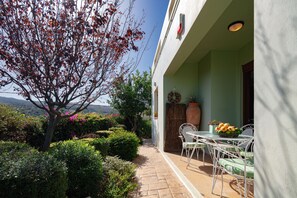 Eine Terrasse mit Tisch und Stühlen, einem Blumentopf und Blick auf die umliegende Landschaft.