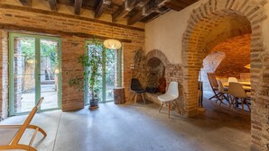 A rustic interior with exposed brick walls, a wooden ceiling, a brick fireplace, and a dining area with chairs and a table. - Historic Casona in Sierra de Gredos – Private Pool, 7 Bedrooms, 14 Guests (Candeleda)