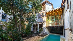 A courtyard with a swimming pool, wooden deck, and potted plants. - Historic Casona in Sierra de Gredos – Private Pool, 7 Bedrooms, 14 Guests (Candeleda)