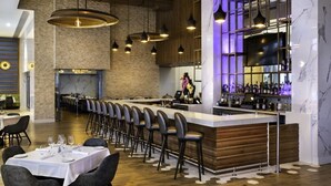 A restaurant with a long counter, multiple bar stools, and a bar area with shelves of bottles. - Elegant 1BR Suite • Large Balcony • Pool – Circ Hotel (Hollywood)