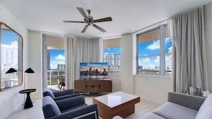 A modern hotel room with a city view, a ceiling fan, a flat-screen TV, and a seating area with a coffee table. - Bright & Spacious 1BR • Big Balcony • Pool (Hollywood)