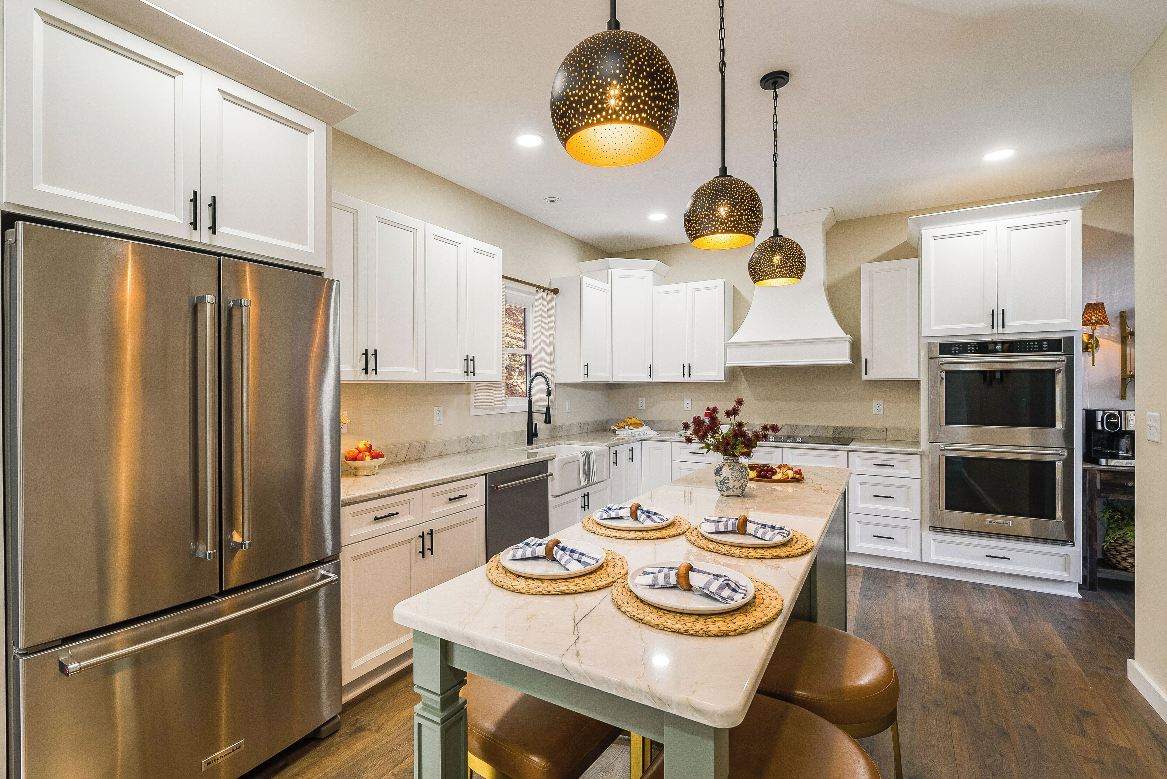 A modern kitchen with stainless steel appliances, white cabinetry, and a marble countertop.