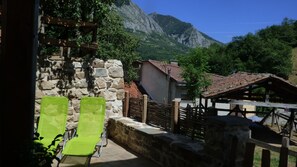 A stone building with a tiled roof, a wooden fence, and a view of mountains. - Rural Apartment Los Riegos in mountain village in P.Natural de Redes, Asturias (Caso)
