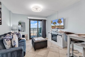A modern living room with a sofa, ottoman, and a dining area with a table and chairs. - Bluewater Resort 309 (Myrtle Beach)