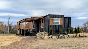 Une cabane moderne, de plain-pied, dotée d’un porche en bois et de fondations en pierre.