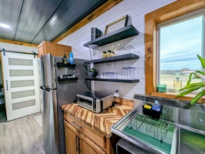 A modern kitchen with a built-in refrigerator, wooden cabinets, a microwave, and a window with a view of the outdoors.