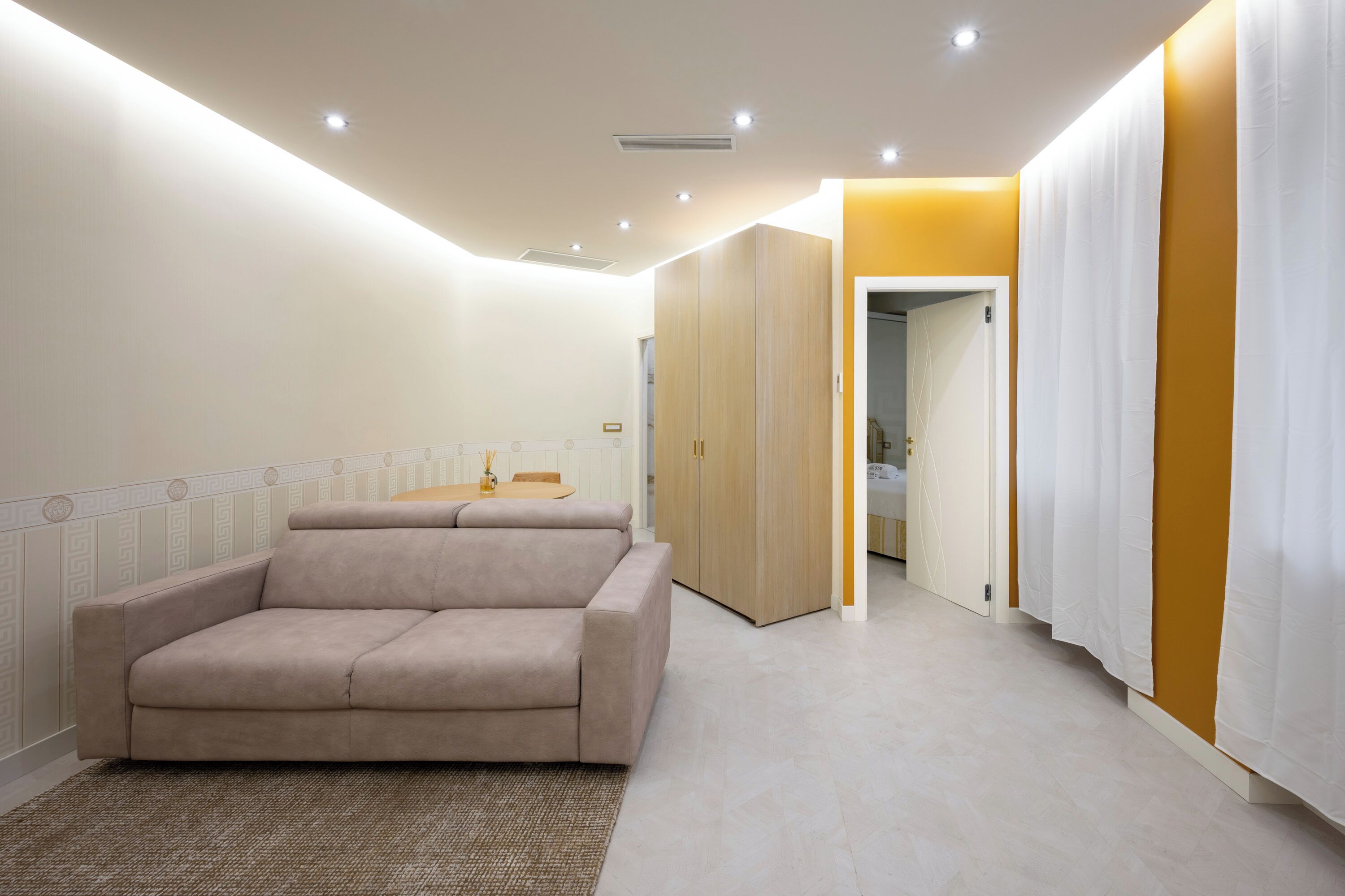 Un soggiorno moderno con un divano beige, un tavolino e un tappeto decorato.