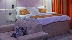 Egy modern hálószoba, amelyben található egy ágy, egy kanapé és egy mennyezeti lámpatest.