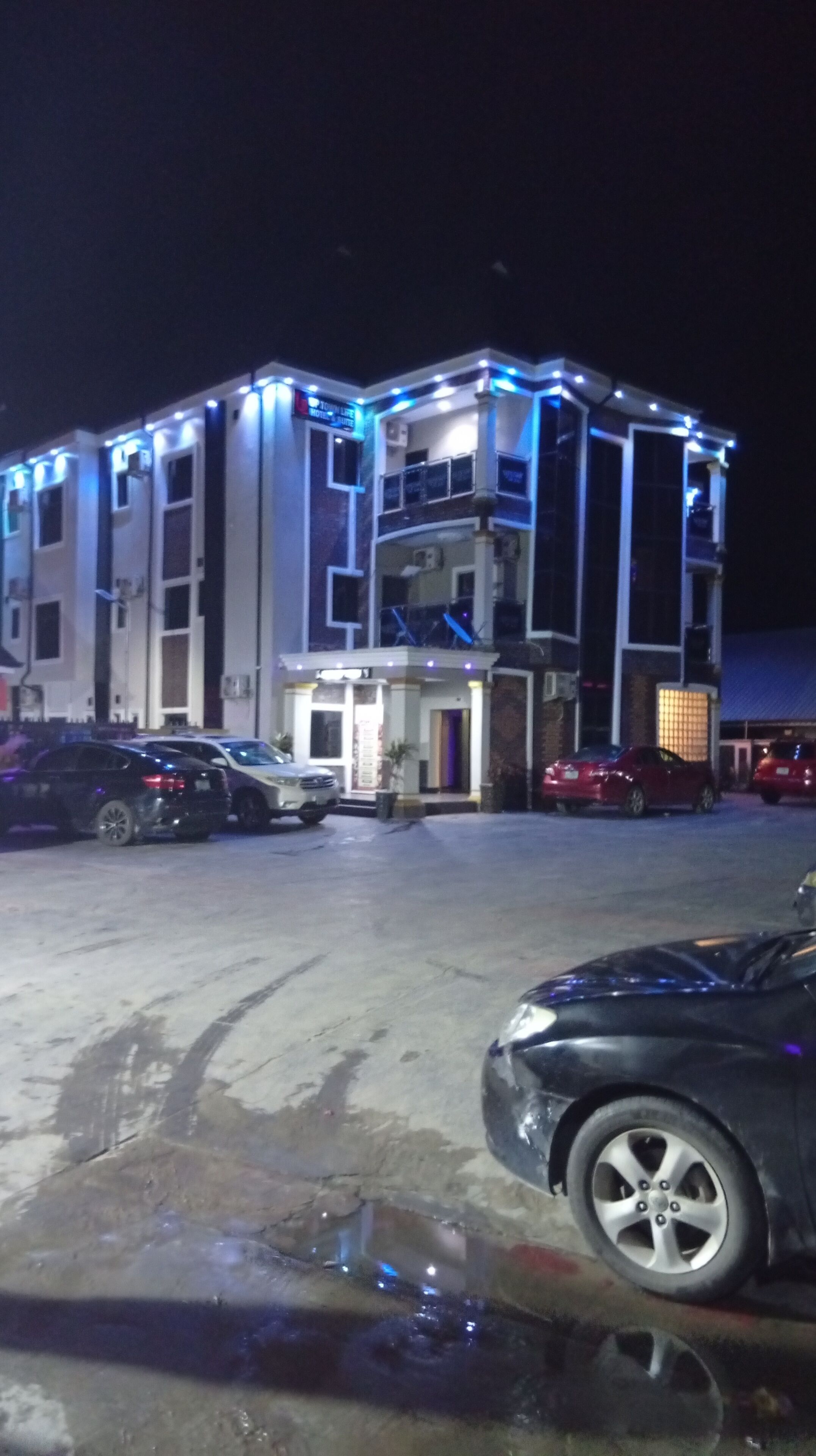 A multi-story building with a central entrance and a parking lot.