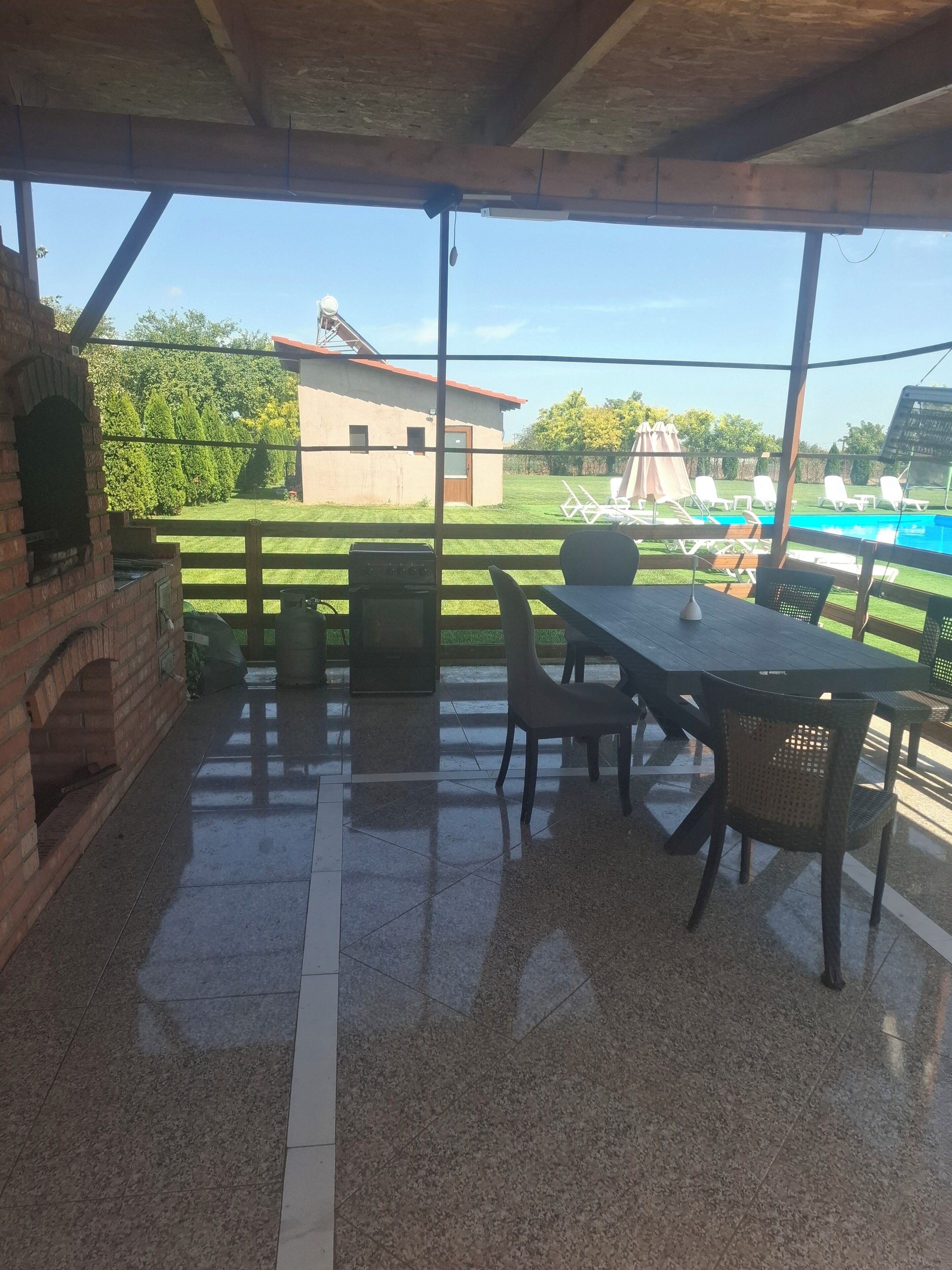 An outdoor patio area with a brick oven, a table, and chairs.