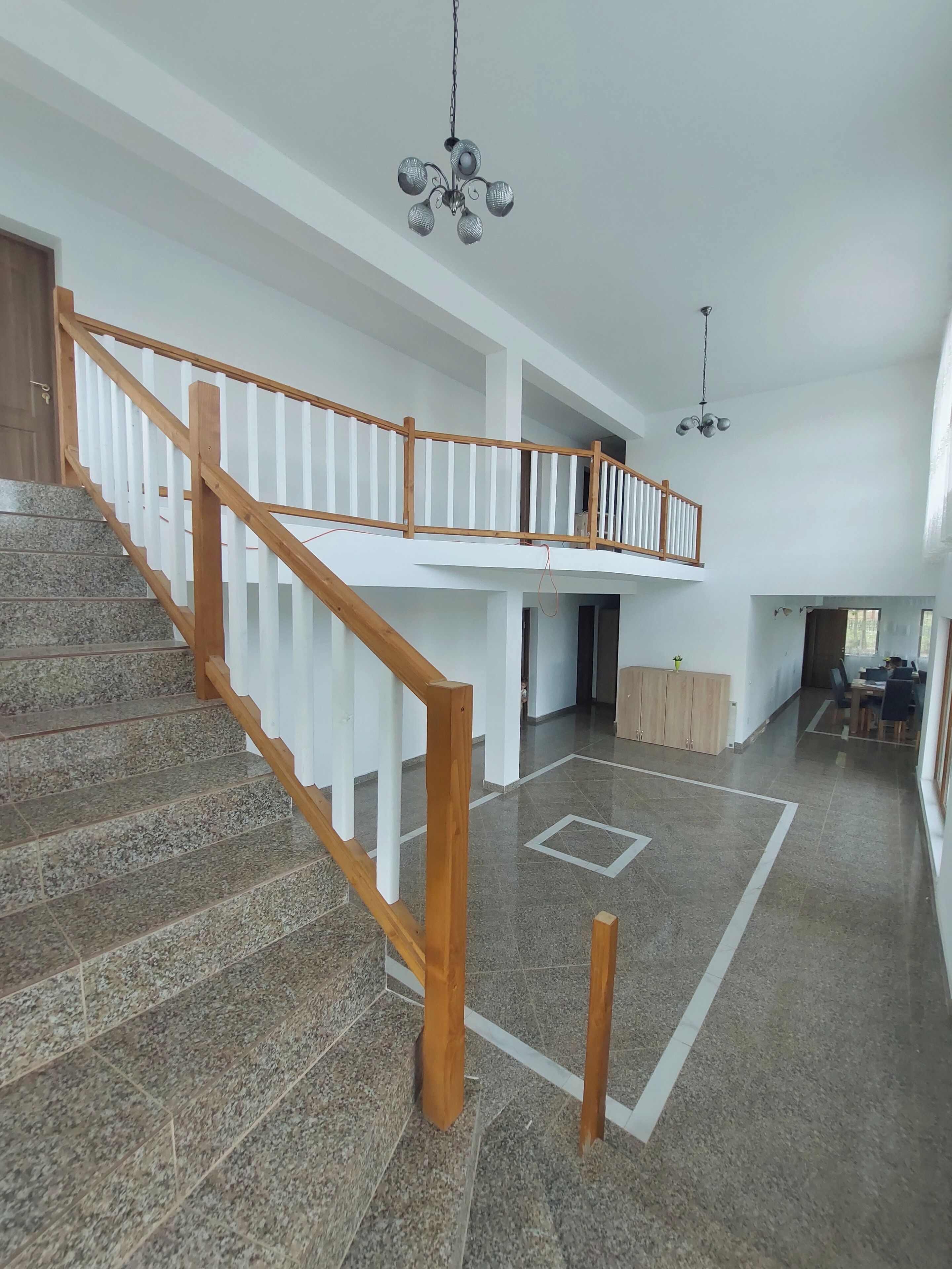 Ein geräumiger Innenraum mit Treppe, einer Chandelüster und einem Essbereich.