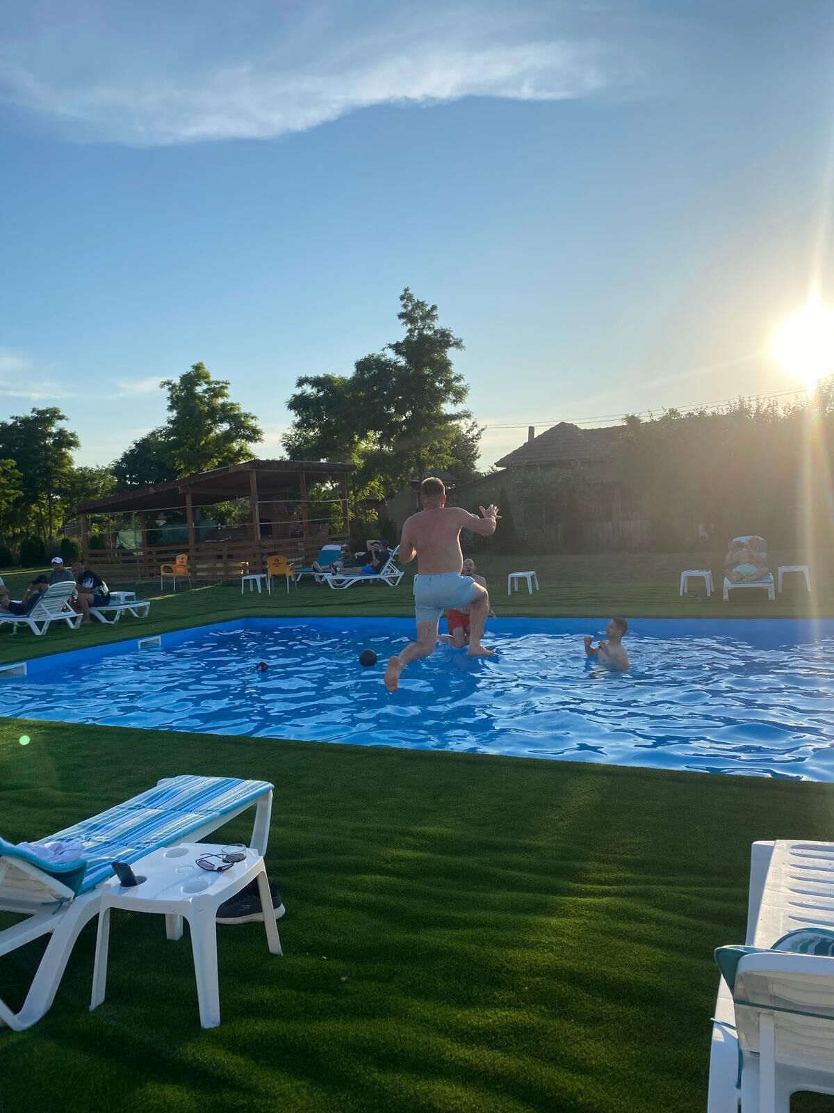 A swimming pool with lounge chairs and a grassy area.
