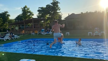 A swimming pool with lounge chairs and a grassy area.
