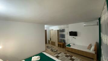 A hotel room with two beds, a TV mounted on the wall, and a small desk with a chair.