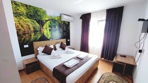 A hotel room with a large bed, a wall-mounted air conditioner, a TV, and a wooden nightstand. - Paradiso Resort (Murighiol)