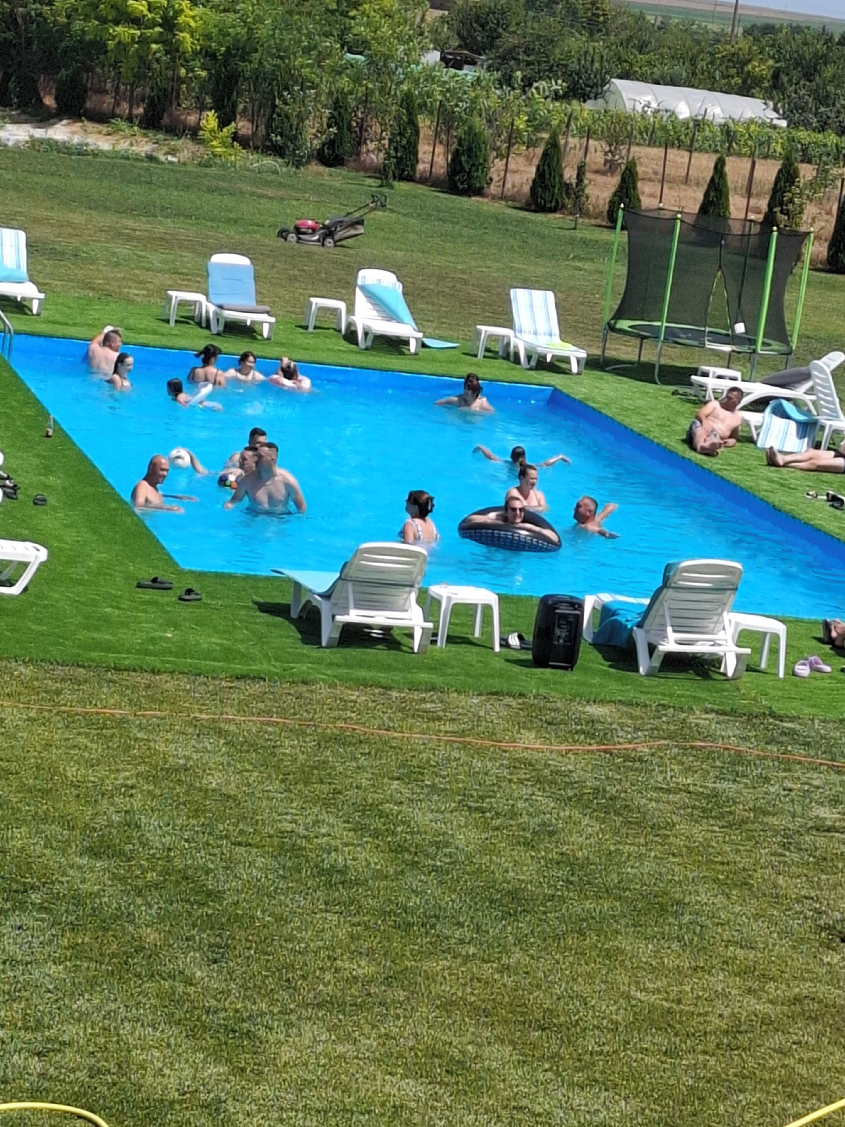 Une piscine entourée de chaises longues et d’une pelouse.