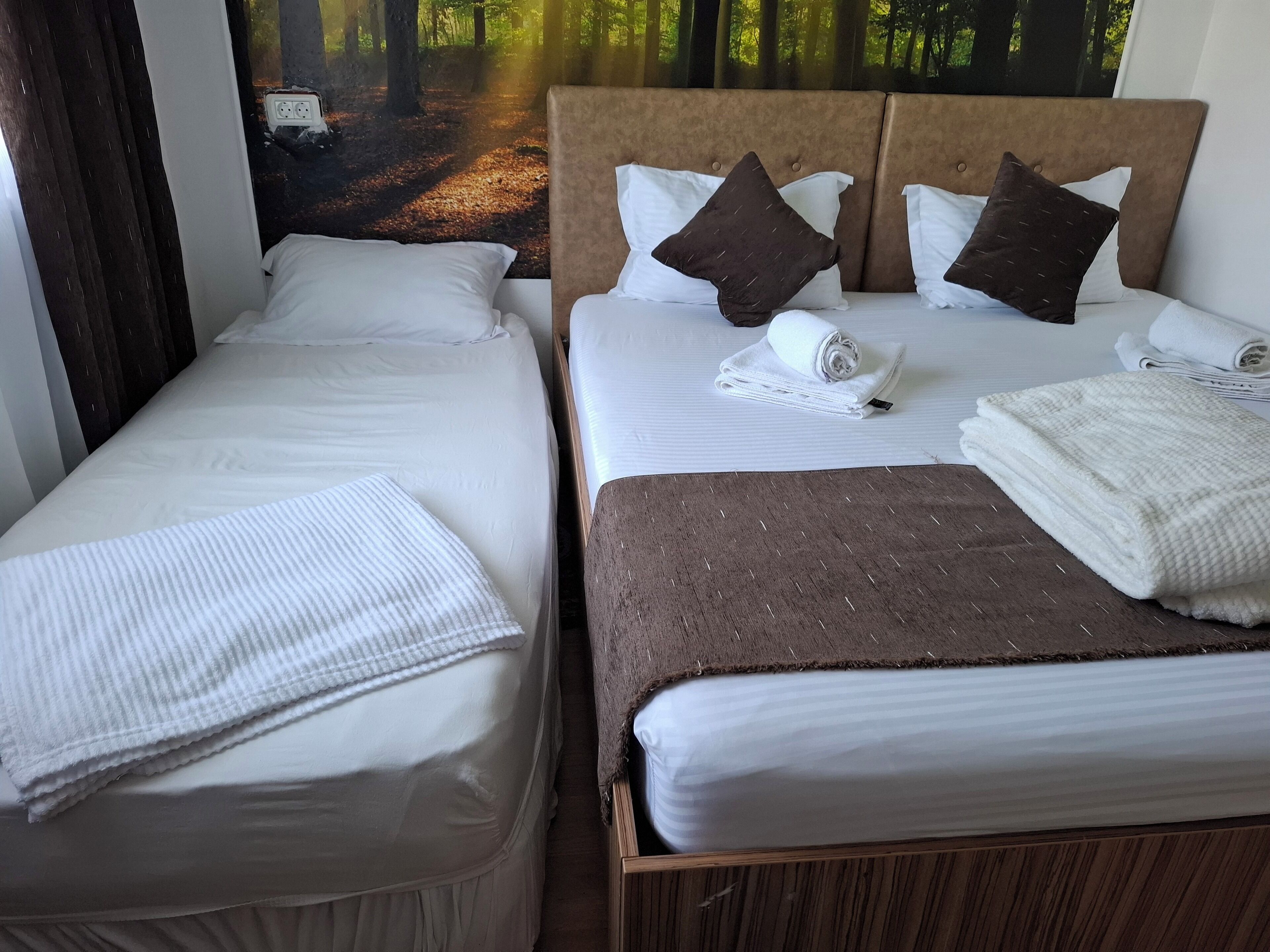 Una habitación de hotel con dos camas, cada una con sábanas blancas y cabeceros marrones.