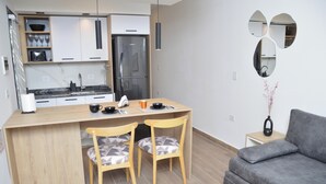 Een moderne keuken met een centraal eiland, houten stoelen, een grijze bank en een klein bijzettafeltje met een vaas.