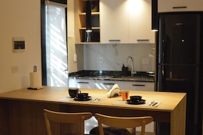 Een compacte keuken met een eethoek, met een houten tafel, stoelen en een koelkast.