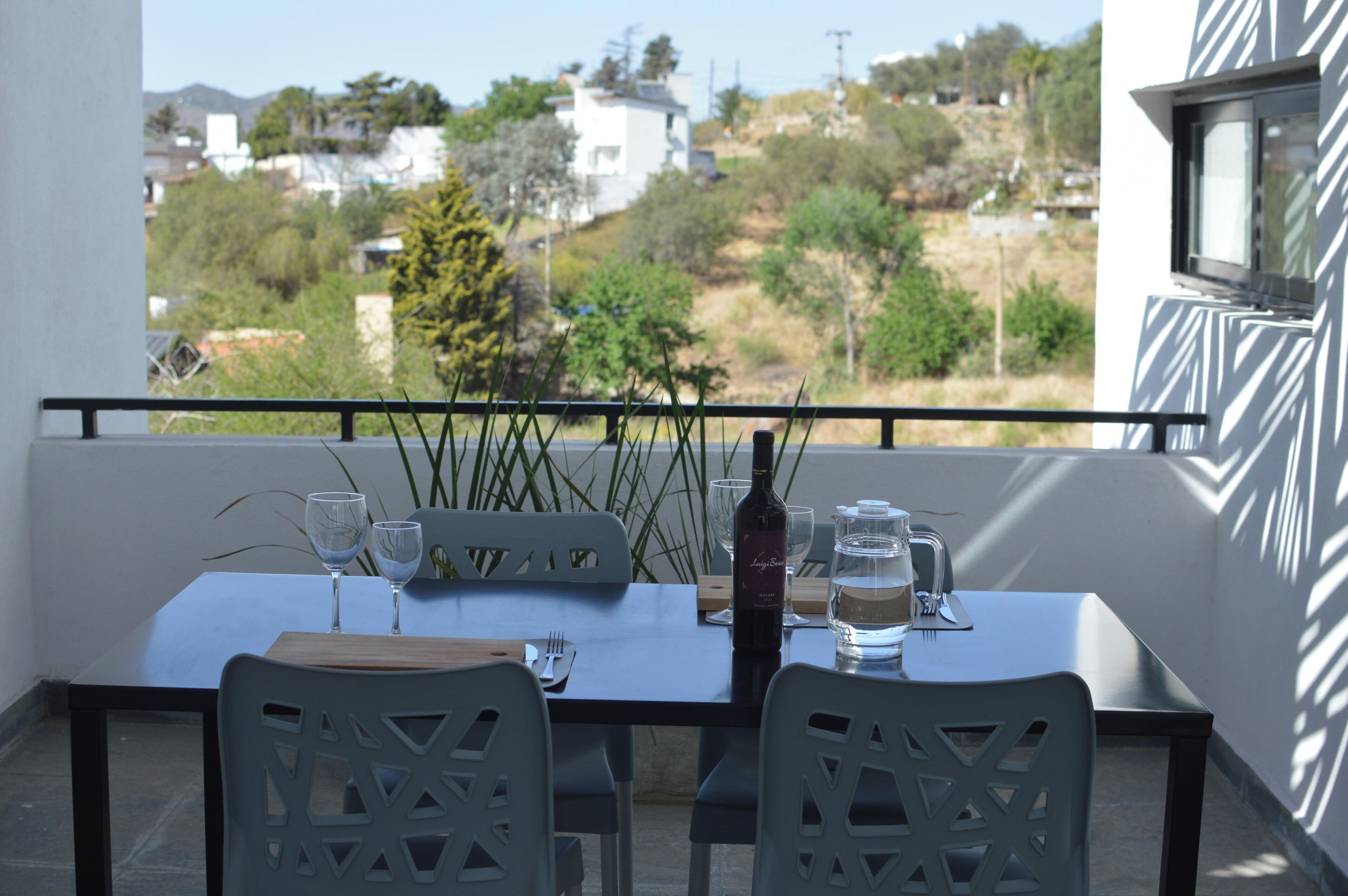 Ein Balkon mit Tisch für zwei Personen, komplett mit einer Weinflasche, Gläsern und einer Wasserflasche.