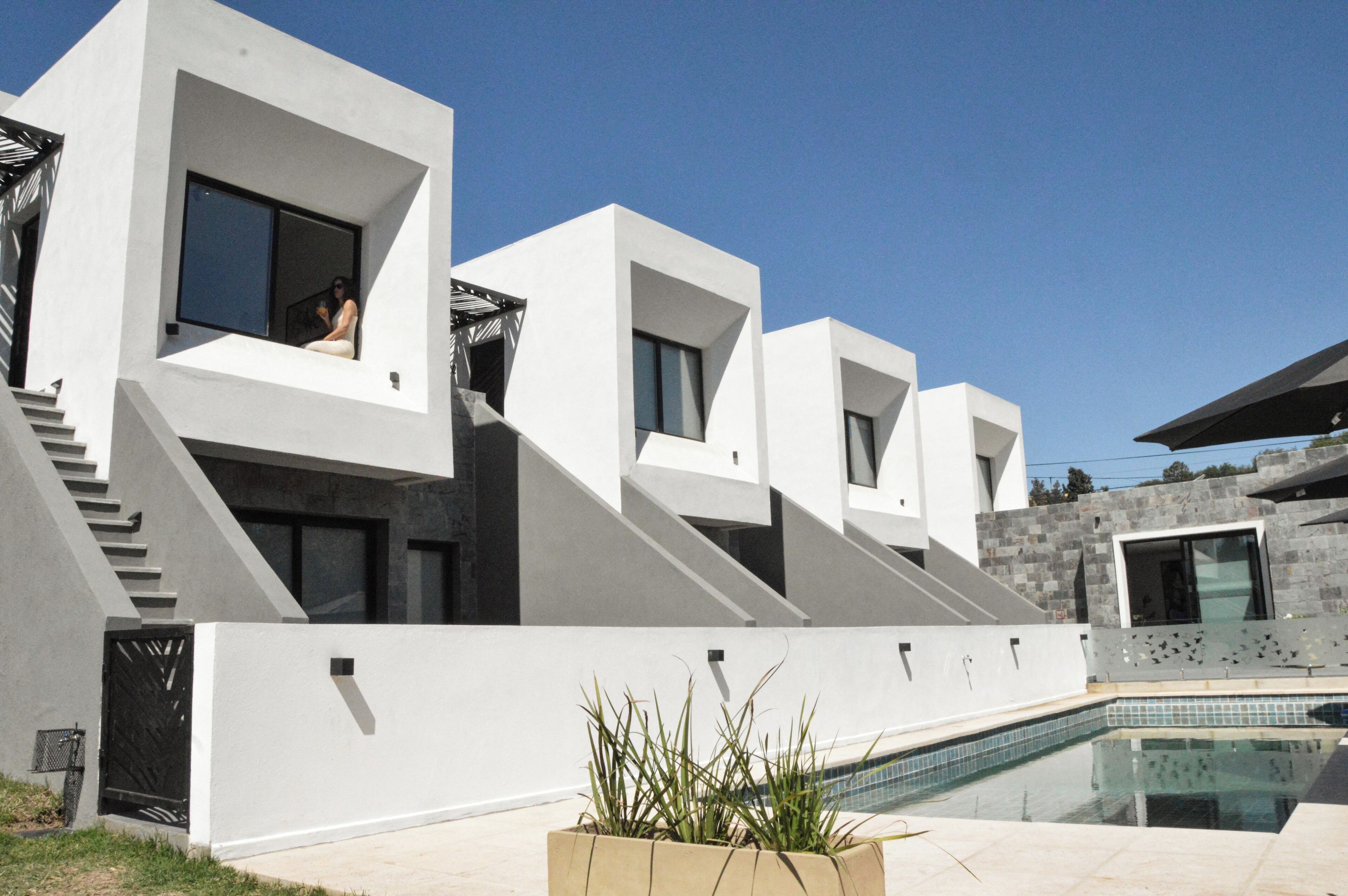 A modern house with a pool, featuring a staircase leading to a balcony.
