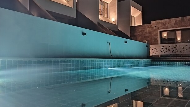 Een modern zwembad met een helder wateroppervlak dat de omliggende architectuur weerspiegelt.