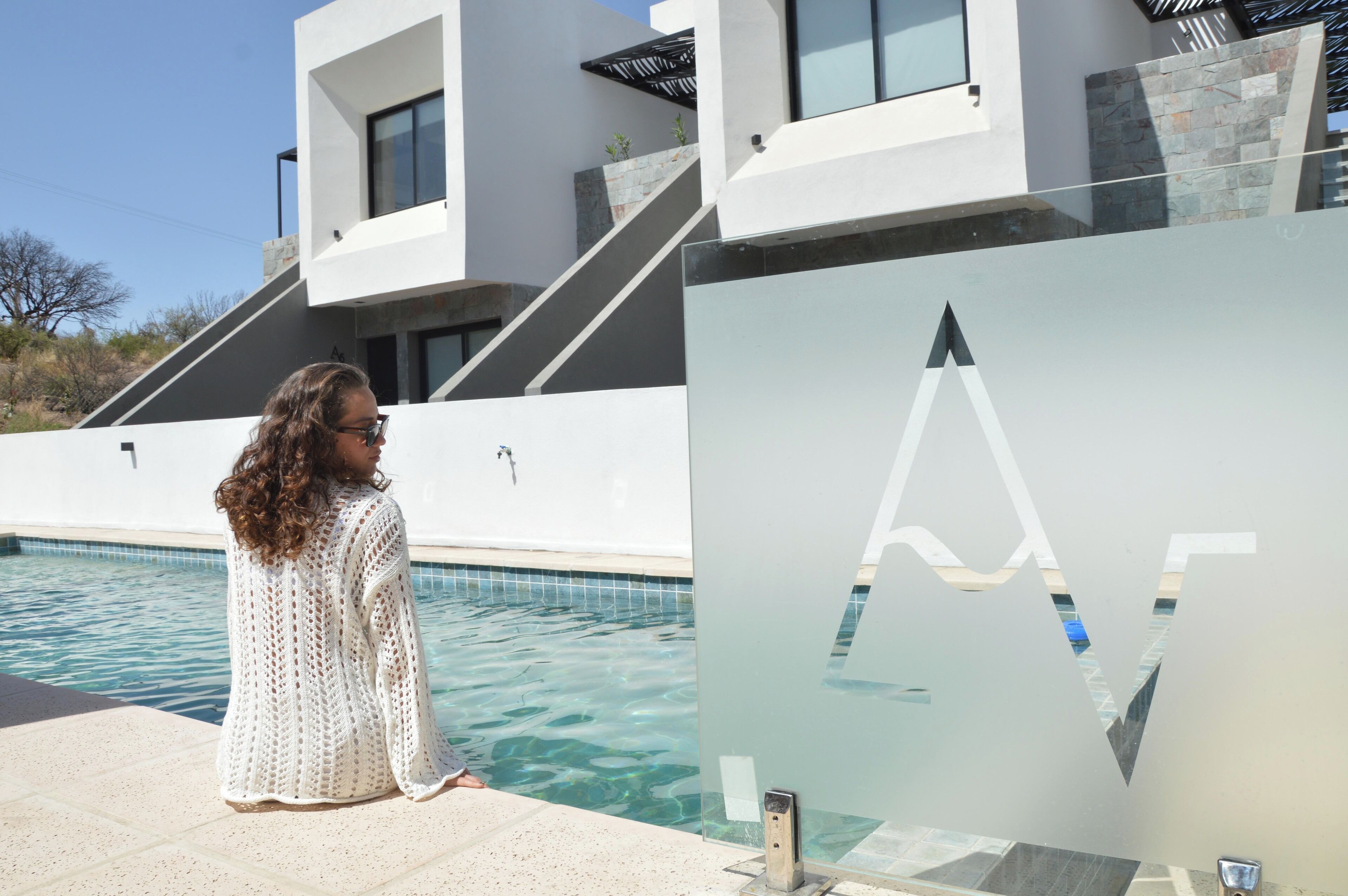 Un edificio moderno con piscina, una pared de vidrio con diseño geométrico y una escalera que conduce a los niveles superiores.