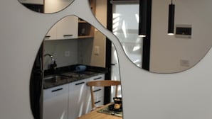 Een moderne keuken met witte kasten, een houten eettafel en een zwart hanglamp.