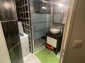 Un baño con lavamanos blanco, espejo y cabina de ducha.
