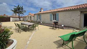 Eine Terrasse mit Tisch, Stühlen, einem Grill und einer Bank.
