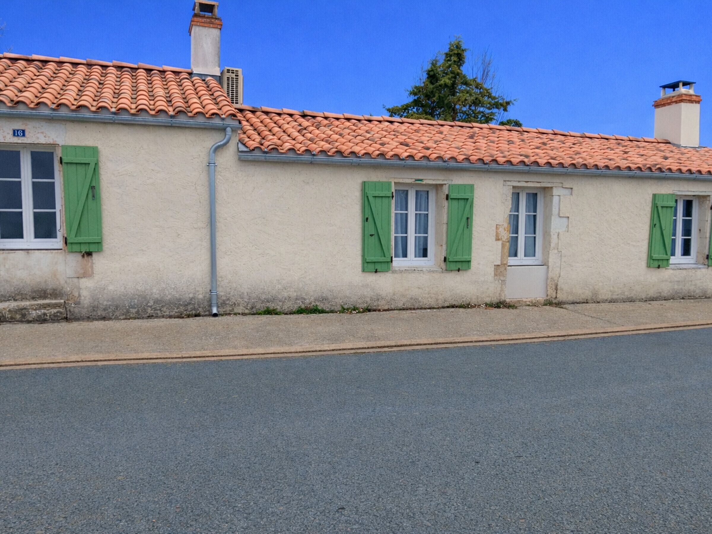 A two-story building with a tiled roof and green shutters.