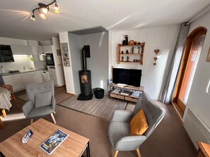 Ein modernes Wohnzimmer mit Kamin, Fernseher und Bücherregal.