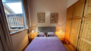 Ein Schlafzimmer mit einem großen Bett, zwei Nachttischlampen, einem Holzschrank und zwei an der Wand befestigten Bildern.
