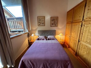 Ein Schlafzimmer mit einem großen Bett, zwei Nachttischlampen, einem Holzschrank und zwei an der Wand befestigten Bildern.