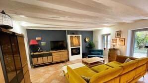 Een woonkamer met een gele bank, een televisie, een houten kast en een rode lamp.