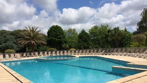 Una piscina rectangular amb una zona solària enrajolada, envoltada de gandules i una tanca de metall baixa.