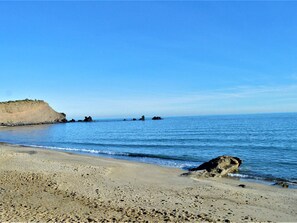 A beach with a sandy shore, rocky outcrops, and calm blue water. - Cozy Studio with Balcony near the Port - Cap d'Agde (Cap d'Agde)