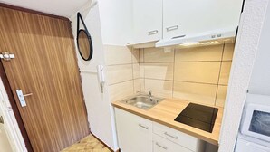 A compact kitchen with white cabinets, a wooden countertop, a sink, and a built-in oven.