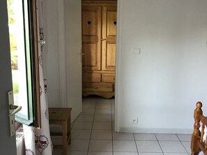 A hallway with a wooden door, a small wooden stool, and a white tiled floor. - Chalet Apartment 2 Bedrooms - 6 Pers, Wifi, Parking (Arâches-la-Frasse)