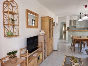 A modern living room with a flat-screen TV, a dining area with a wooden table, and a kitchen with stainless steel appliances. - Exclusive apartment 50m from the beach with pool in L'Escala (L'Escala)