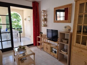 A living room with a television, wicker furniture, and a view of the outdoors. - Exclusive apartment 50m from the beach with pool in L'Escala (L'Escala)