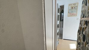 Ein schmaler Flur mit weißer Wand, einem gemusterten Vorhang und einem Poster.