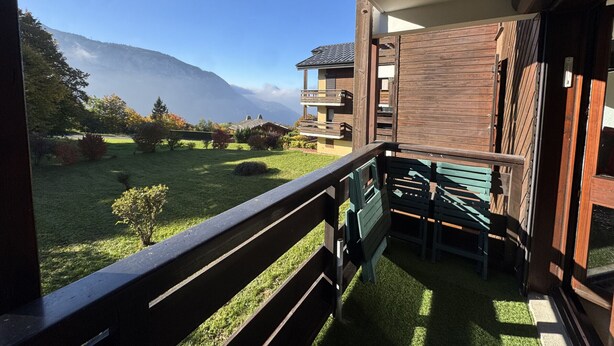 Ein Balkon mit Blick auf einen Berg und einen Garten.