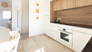 Eine moderne Küche mit weißen Schränken, einer Holzarbeitsplatte und einem eingebauten Backofen.
