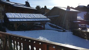Un edificio de madera con techo nevado, una zona cubierta y un coche aparcado cerca.